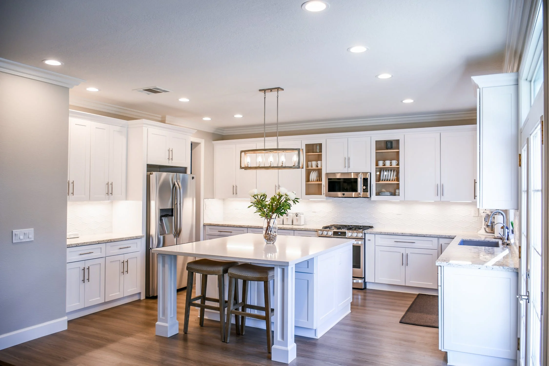 Bright white custom kitchen with center island and stainless appliances